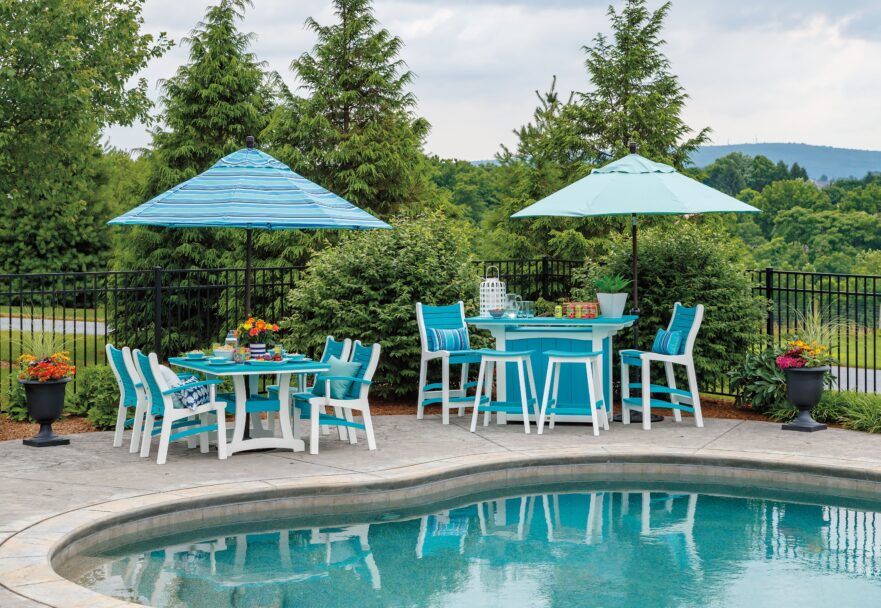 outdoor setting with pool and two sets of outdoor tables and chairs with umbrellas