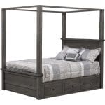 Dark gray hardwood canopy bed with light gray and white bedding and built-in drawers in the bed frame under the mattress.