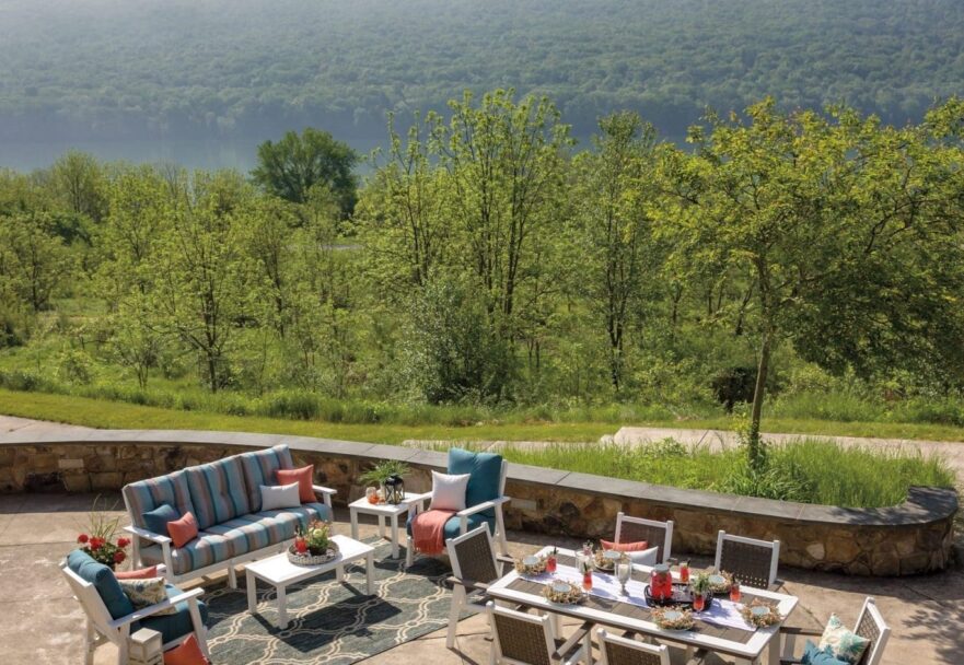 Overhead view of poly lumber furniture on a back stone patio with a brown and white dining set and a blue and white couch set.