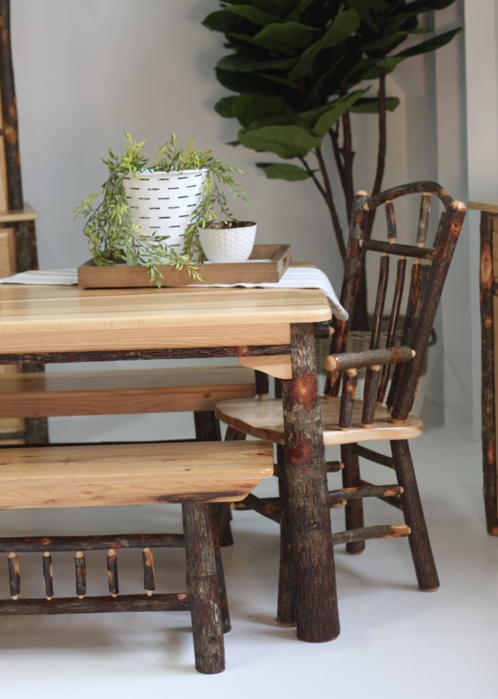 Rustic log dining set with 2 dining benches, an end chair with arms, and a wood tray with a plant and 2 decorative pots.
