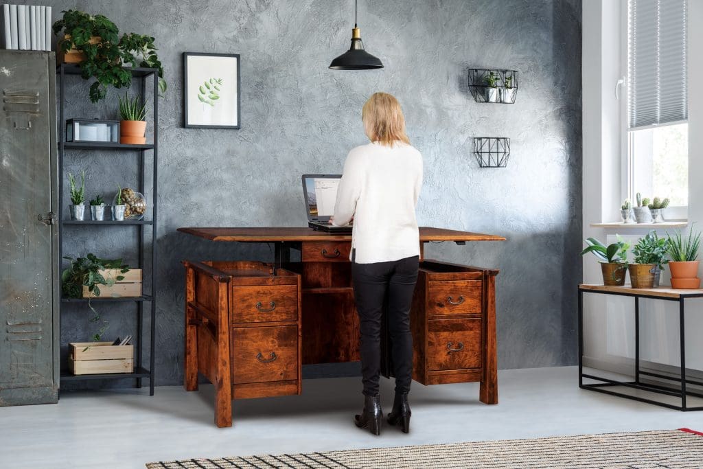 woman in front of an artesa sit to stand desk in an office