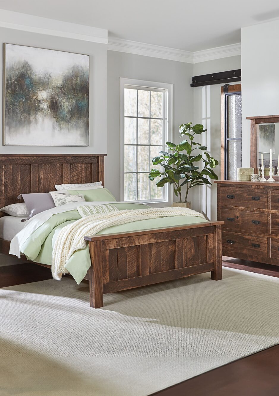 Bedroom with light gray walls, brown wood flooring, a large white rug, a hardwood rough sawn Dumont bed, and a matching rough sawn dresser and nightstand.