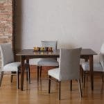 A brown hardwood dining table with 4 gray upholstered dining chairs.
