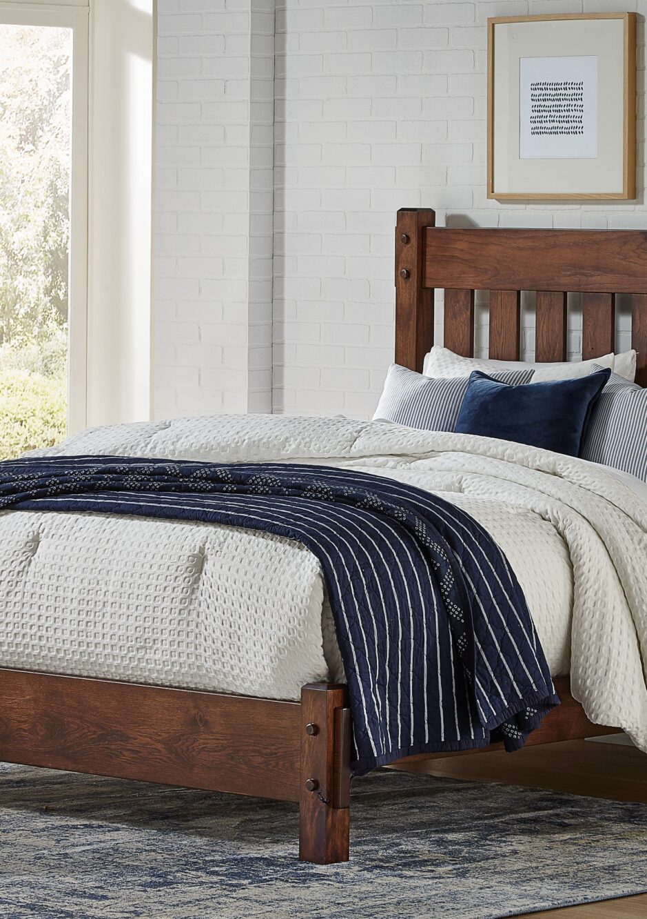 Brown hardwood bed with white and navy blue bedding.
