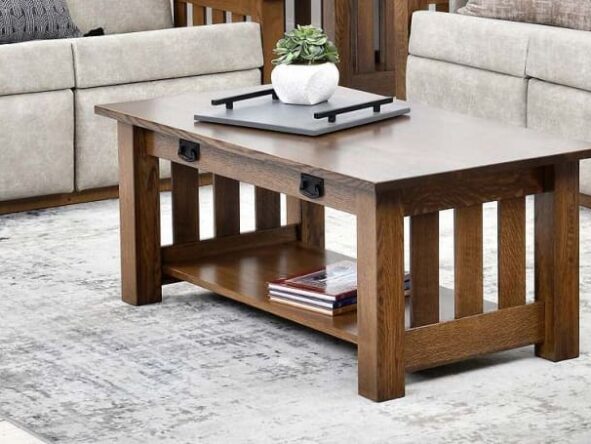 Close up of a hardwood coffee table with black hardware and light colored couches in the background.
