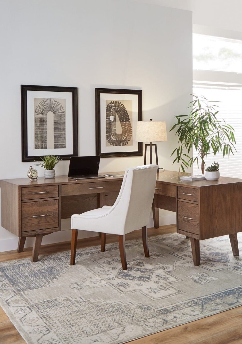 l-shaped office desk with six drawers, a white desk chair, and some paintings, plants, and a computer to decorate
