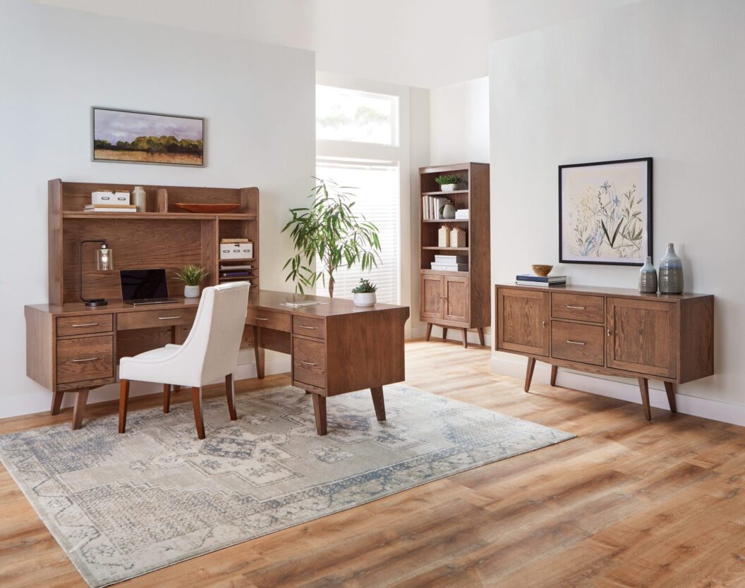 Home office with hardwood L-shaped desk, a white upholstered office chair, a hardwood credenza, and a hardwood bookcase.