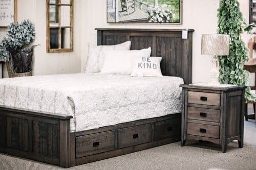 bedroom set up with a bed with underbed drawer storage and a three-drawer nightstand